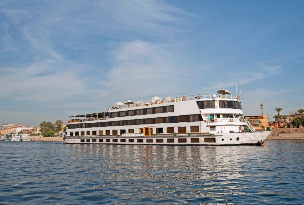 White cruise ship on calm water under blue sky.