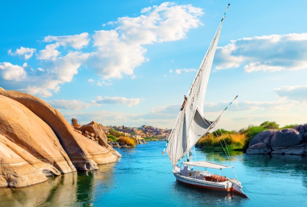 Sailboat navigating a serene river landscape.