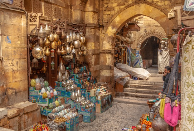 Narrow market alley filled with vibrant pottery and goods.