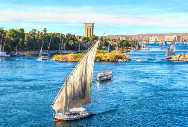 Sailboats on a river with green banks.