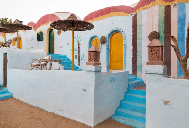 Colorful houses with blue stairs and outdoor seating.