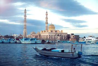 Boat passing by a mosque along the coast.